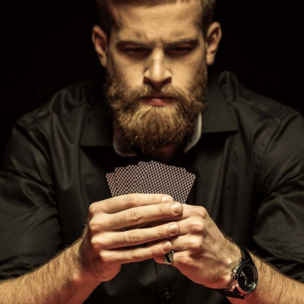a man concentrating while looking at his hand holding poker cards