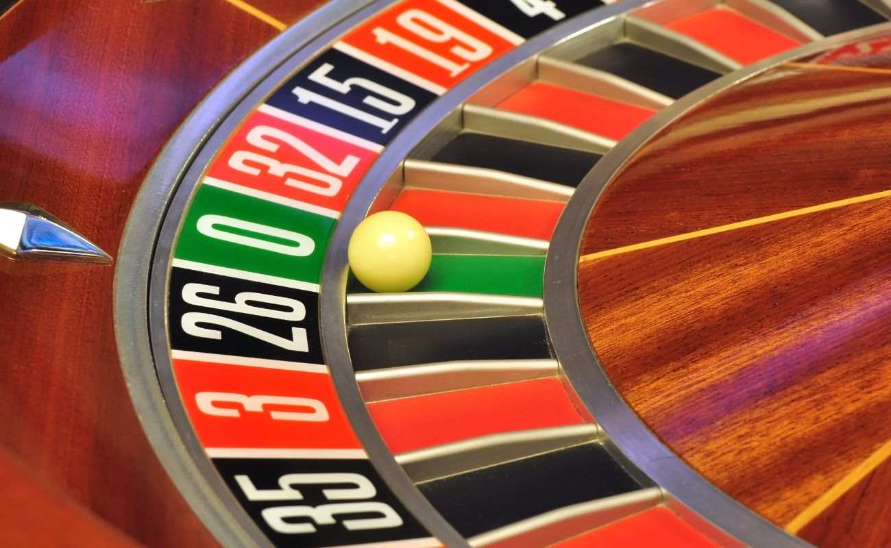 close up of a little white roulette ball on the number zero in a wooden roulette wheel in a casino