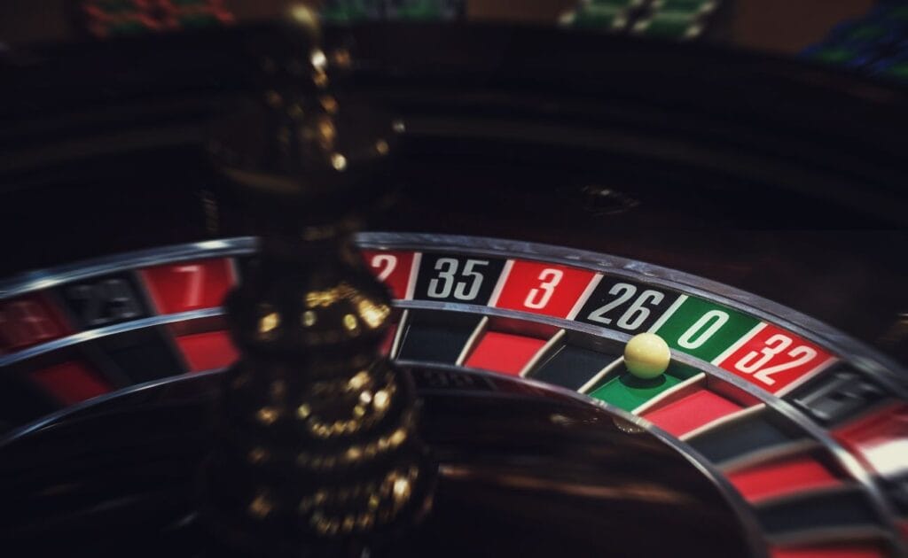 close up of a little white roulette ball on the number zero in a wooden roulette wheel in a casino