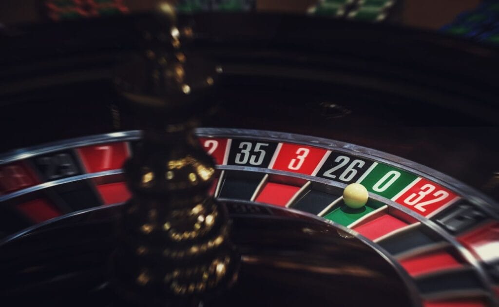 close up of a little white roulette ball on the number zero in a wooden roulette wheel in a casino 