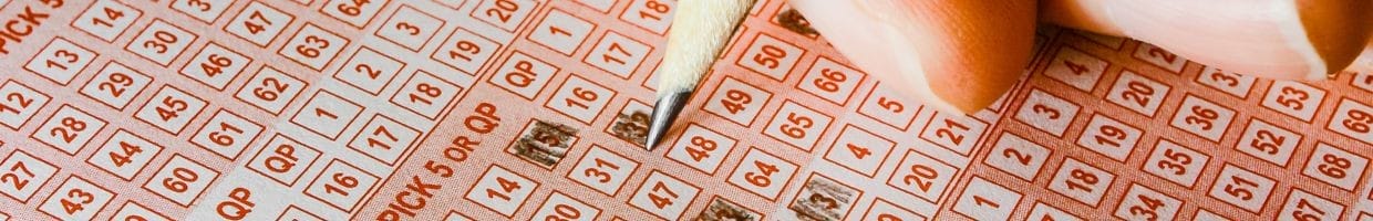 a person using a pencil to fill in numbers on a Keno ticket