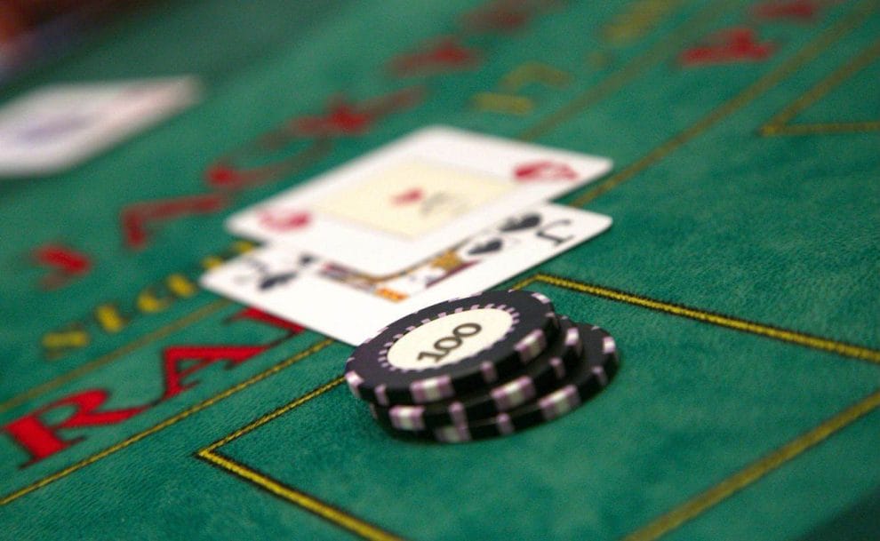 black poker chips in front of two playing cards that have been placed face-up on a green felt blackjack table in a casino