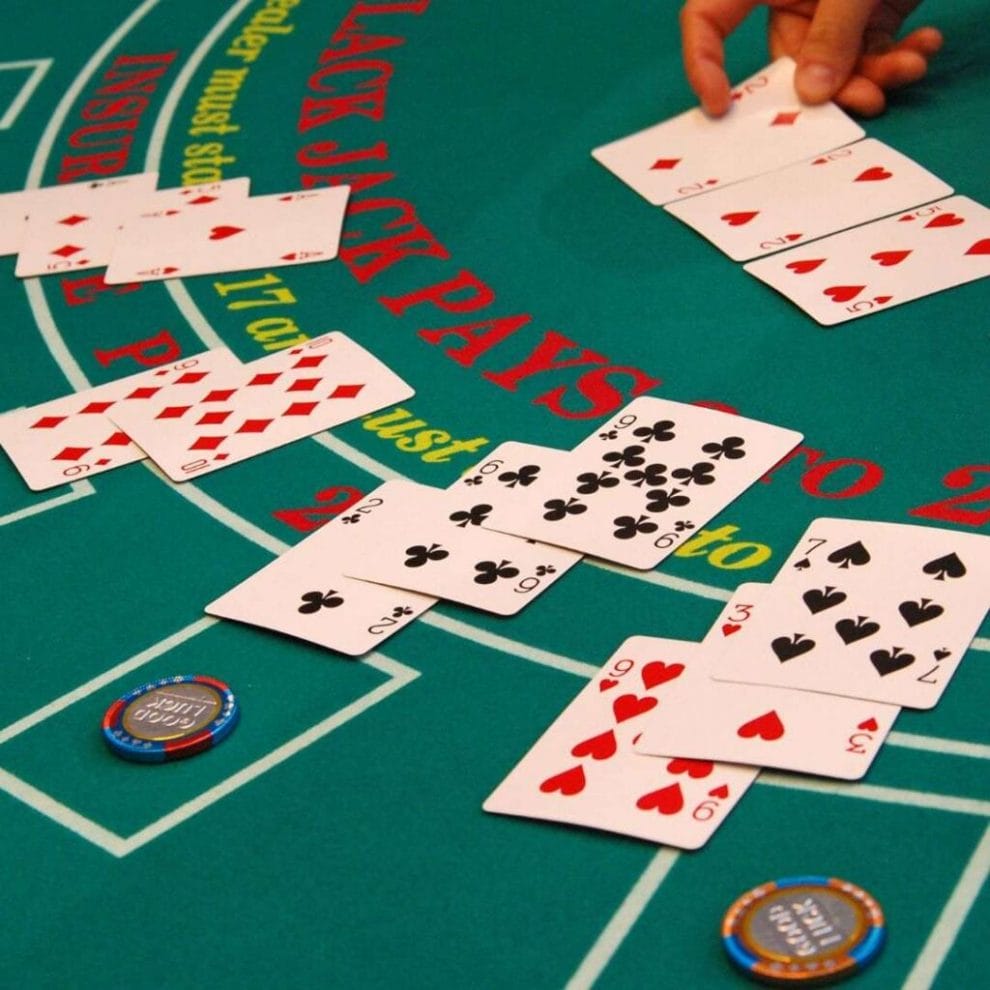 a dealer is placing playing cards face up on a green felt blackjack table with poker chips on it in a casino