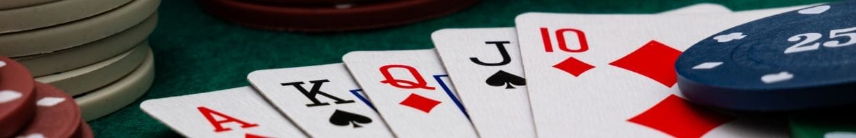a royal straight poker hand in between stacks of poker chips on a green felt poker table