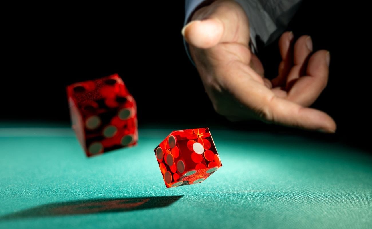 a person throws two red six-sided dice on a craps table in a casino