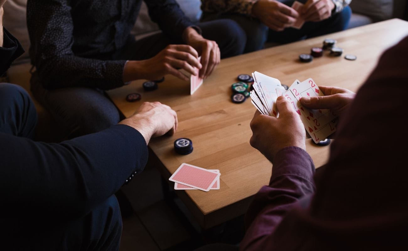 a group of people playing poker together on a wooden coffee table