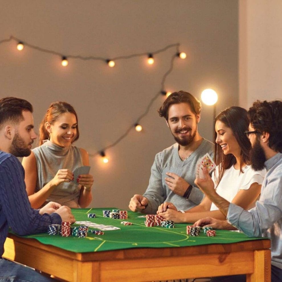 friends playing poker together at home on a dining table with a green felt poker cloth on it
