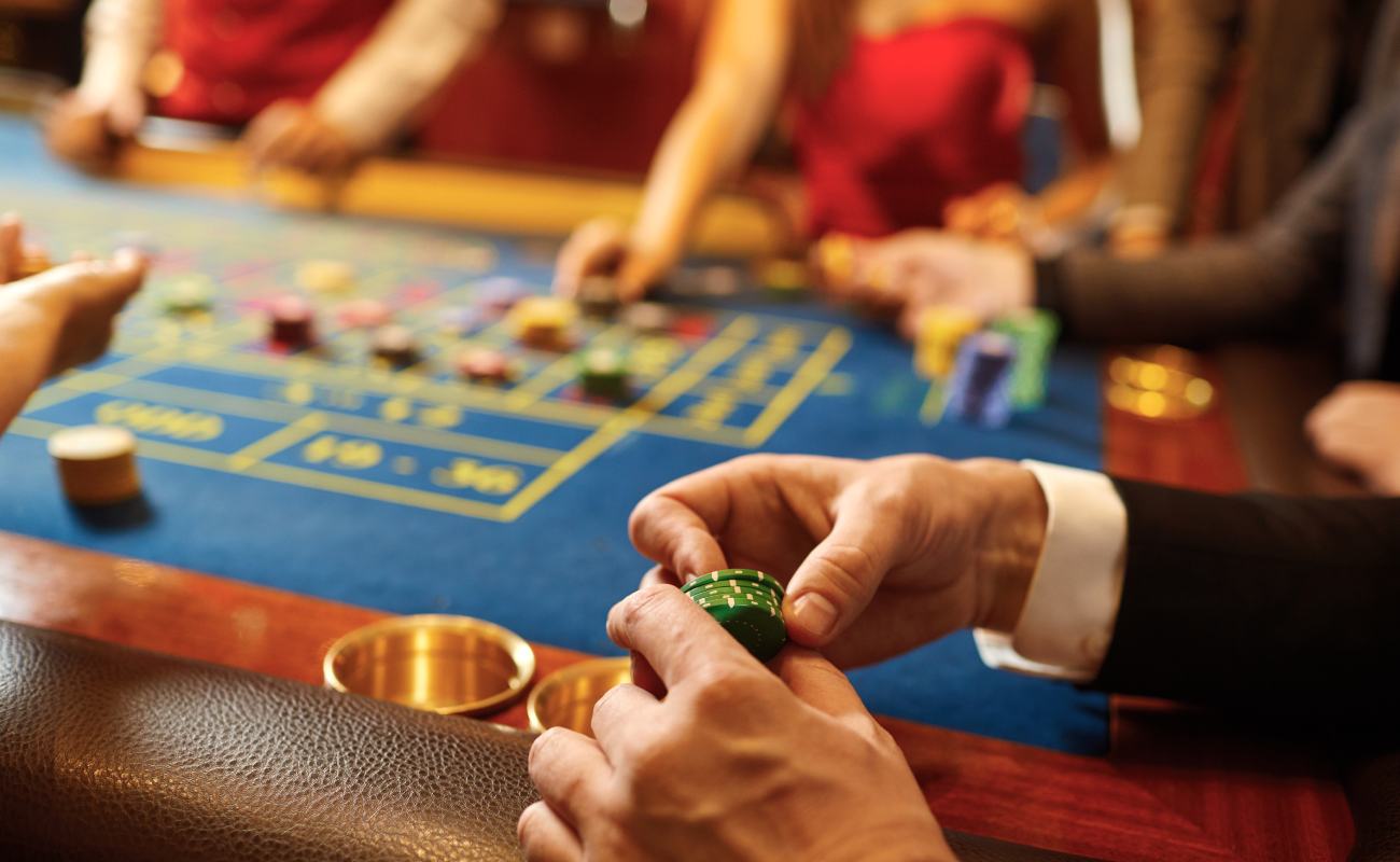 A man holding casino chips between his fingers at a roulette table.