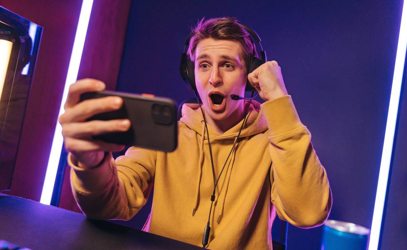 a man cheering while wearing a gaming headset and holding a cellphone