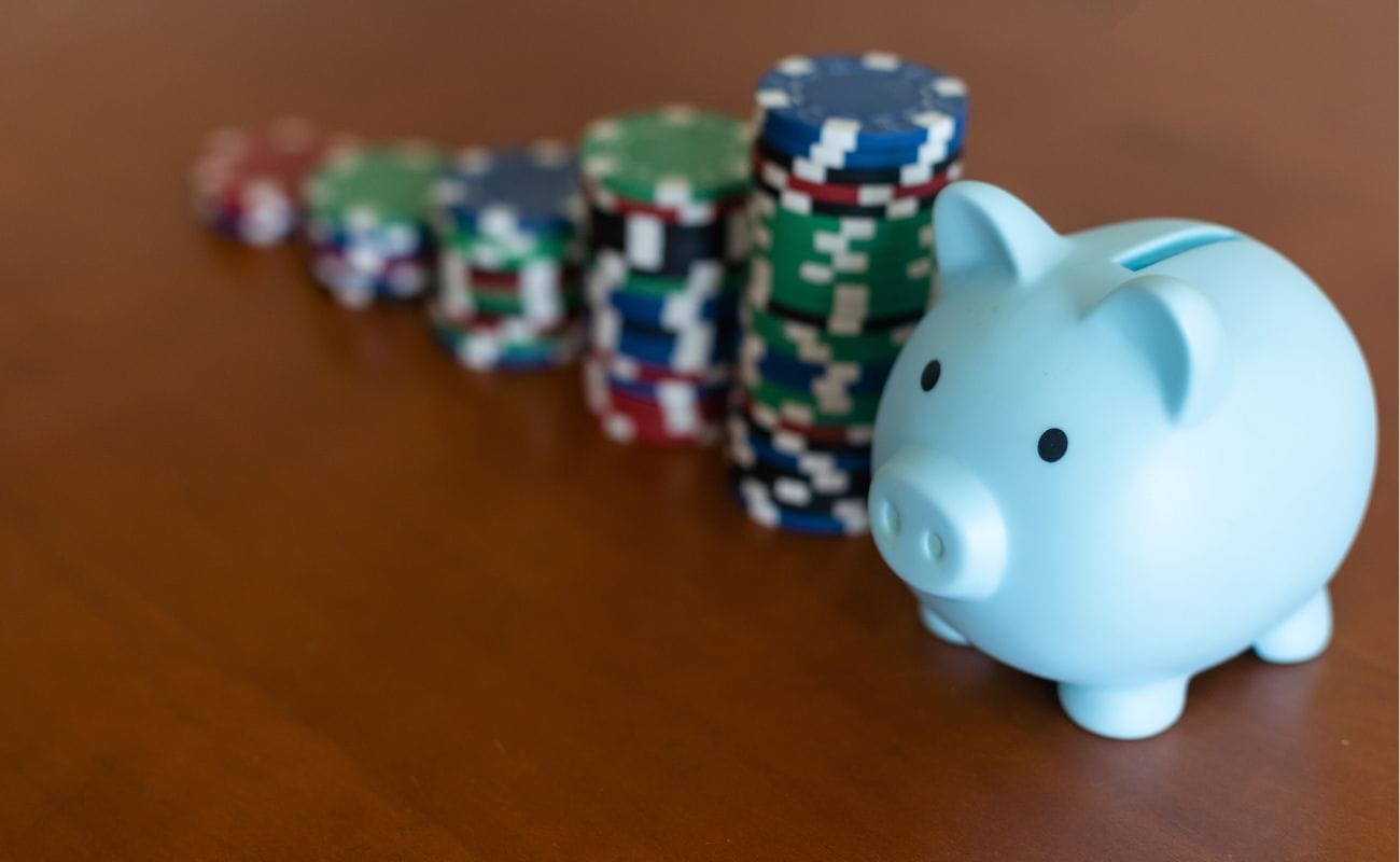 a piggy bank on a wooden surface next to stacks of poker chips lined up next to each other from tallest to shortest 