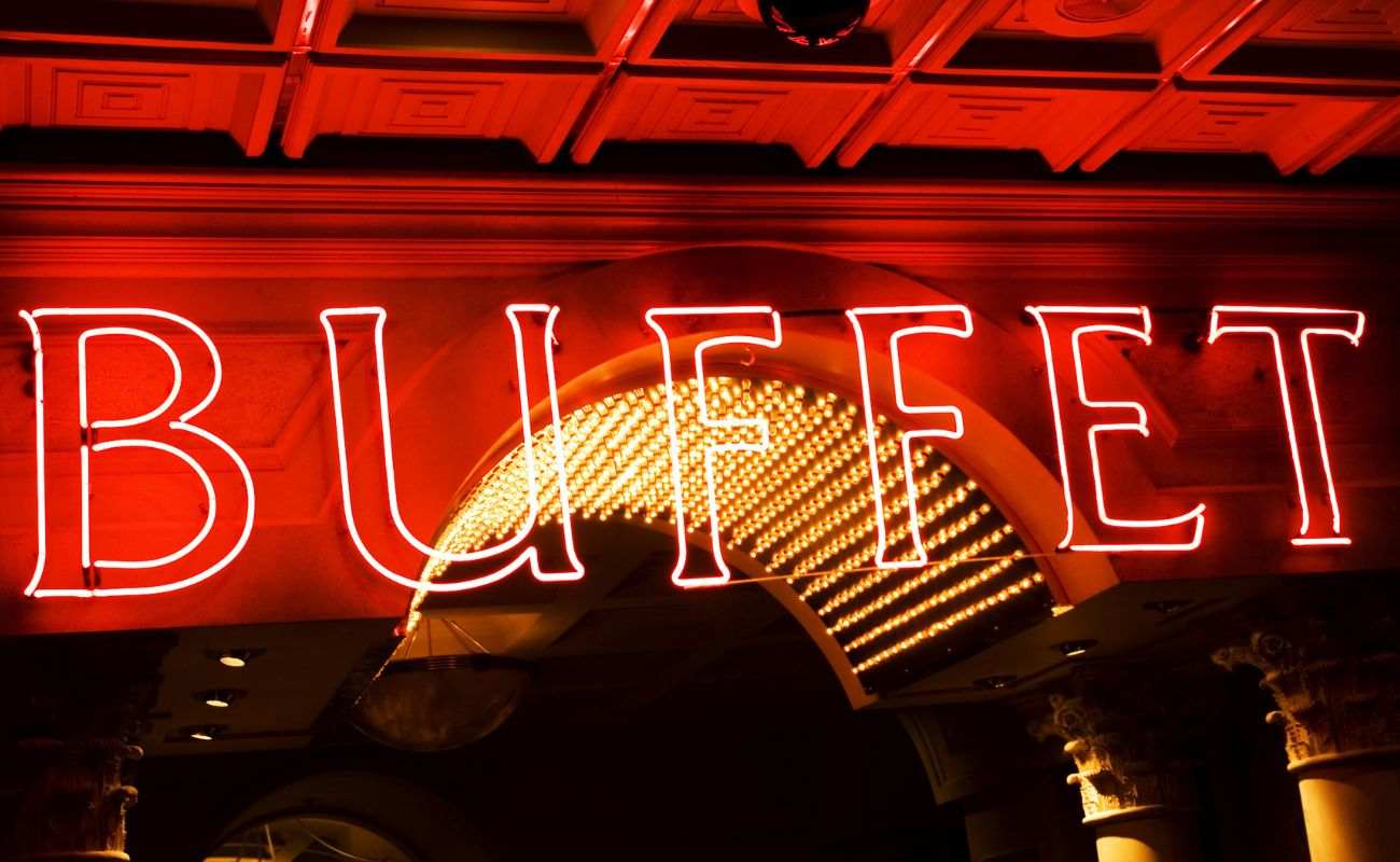 A red neon buffet sign over the arched entrance to a casino restaurant. 