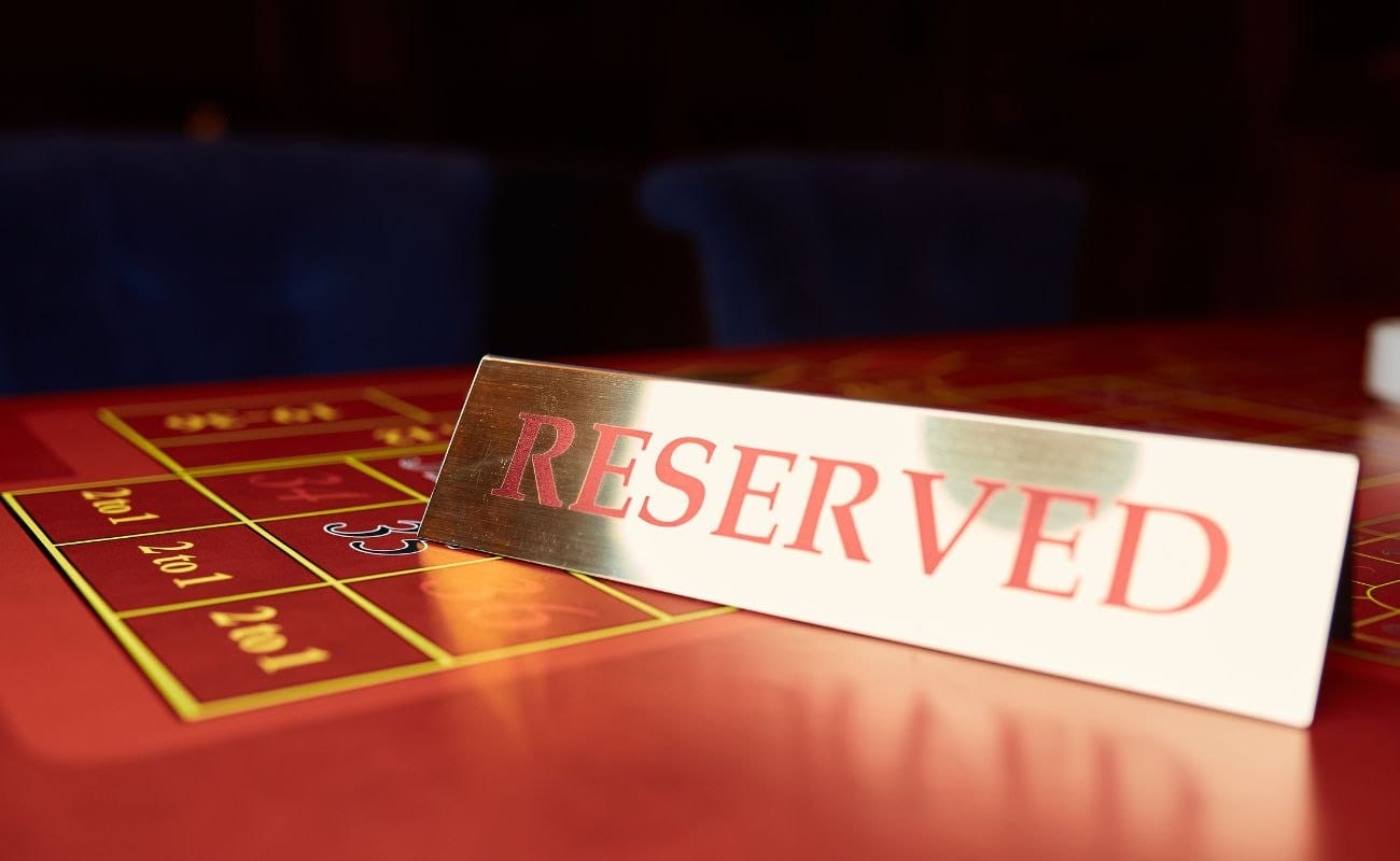 A close up of a restaurant’s “reserved” sign on top of a red roulette table. 