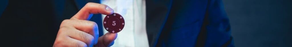 A person holding a poker chip with a 5 on it