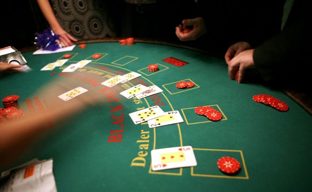 A blackjack dealer distributing cards to players at the blackjack table, with casino chips placed on the table.