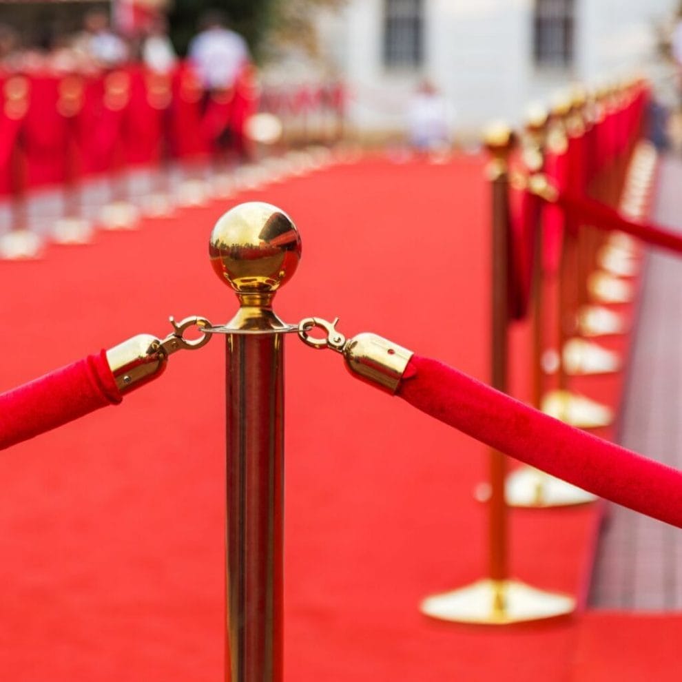 golden stanchions and red ropes forming the barrier of a celebrity red carpet