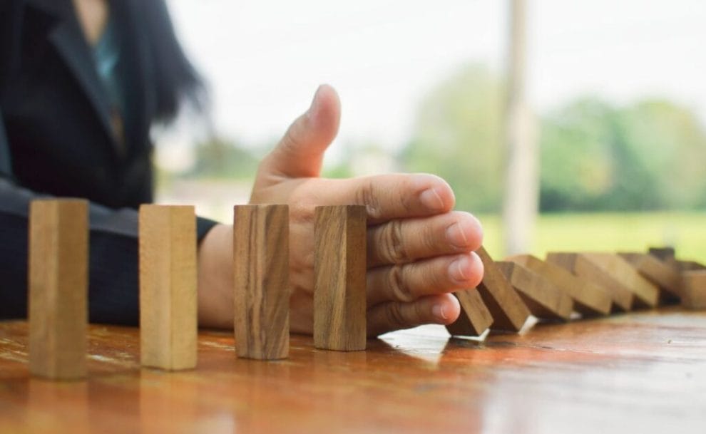 A hand preventing wooden dominoes from touching.