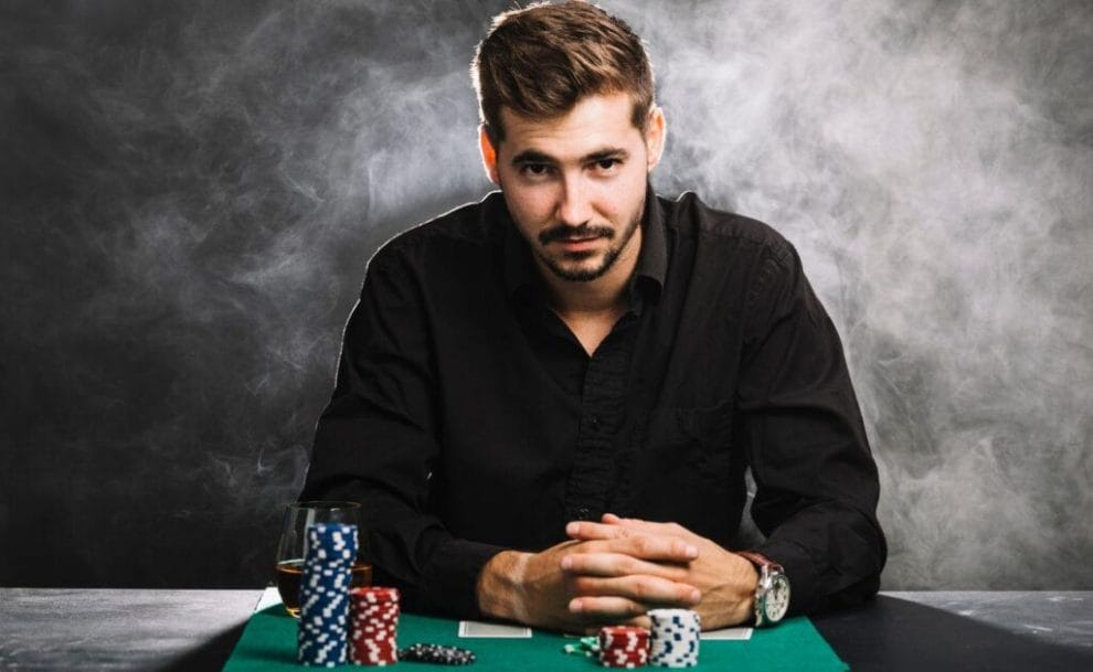 Man sitting at a table, with poker chips stacked in front of him.