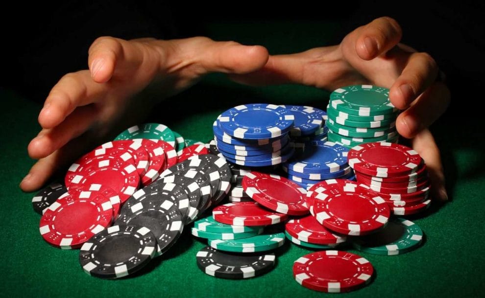Hands reaching out to grab casino chips placed on a poker table.