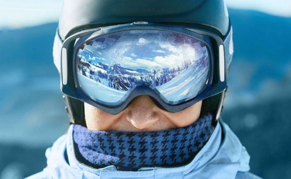 a close up of a person wearing ski goggles that reflect the snowy terrain in front of them
