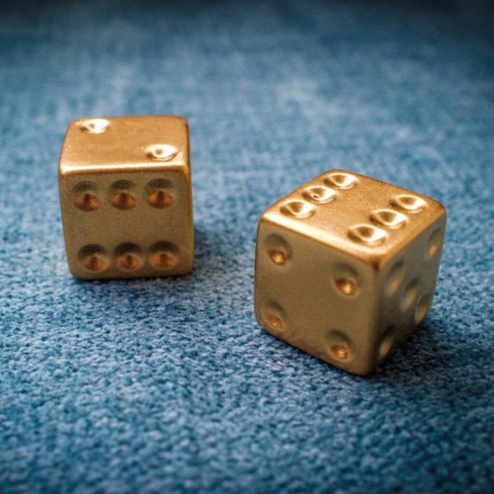 a pair of lucky golden gambling dice on a blue felt surface