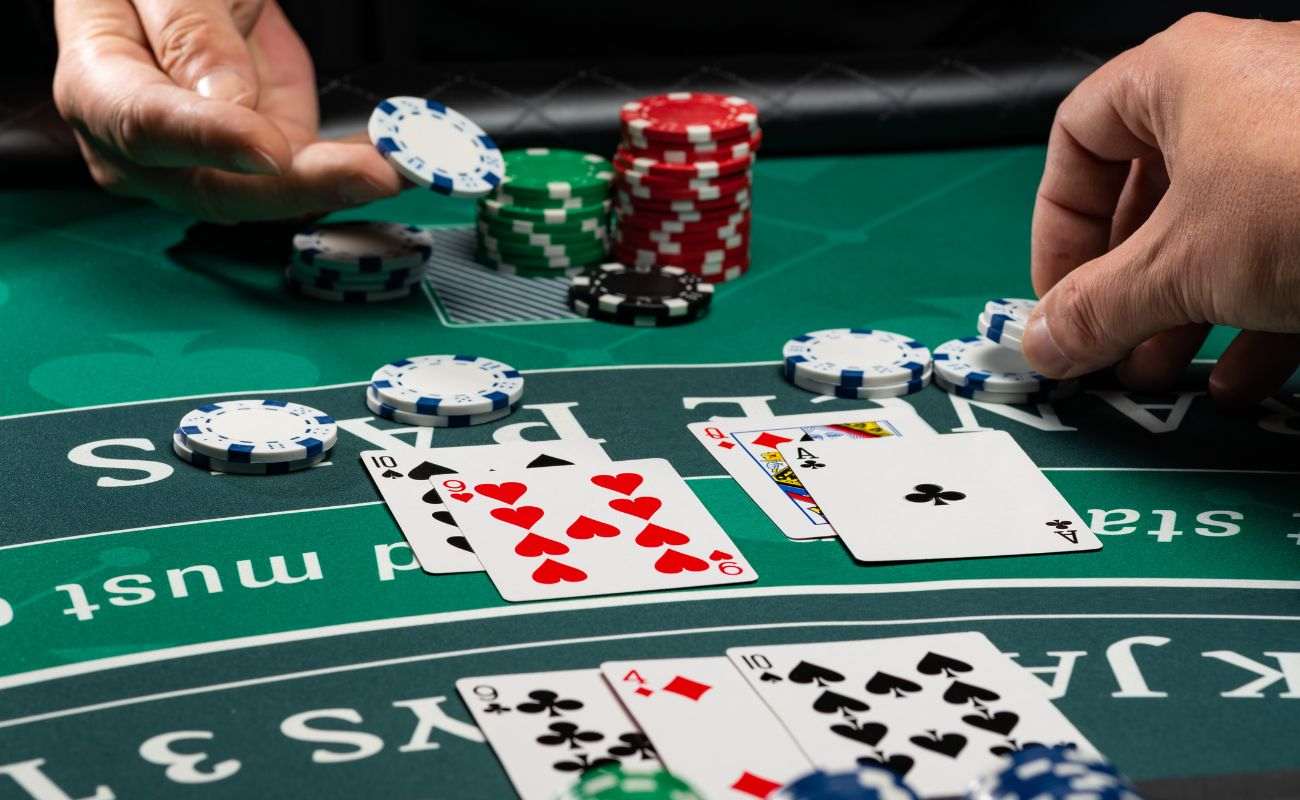 Hands collecting chips from a blackjack table, and there are playing cards placed on the table.