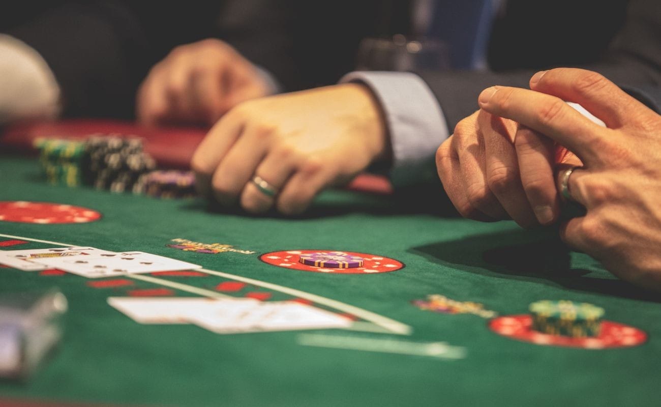 People placing bets around a blackjack table, with playing cards arranged on the table