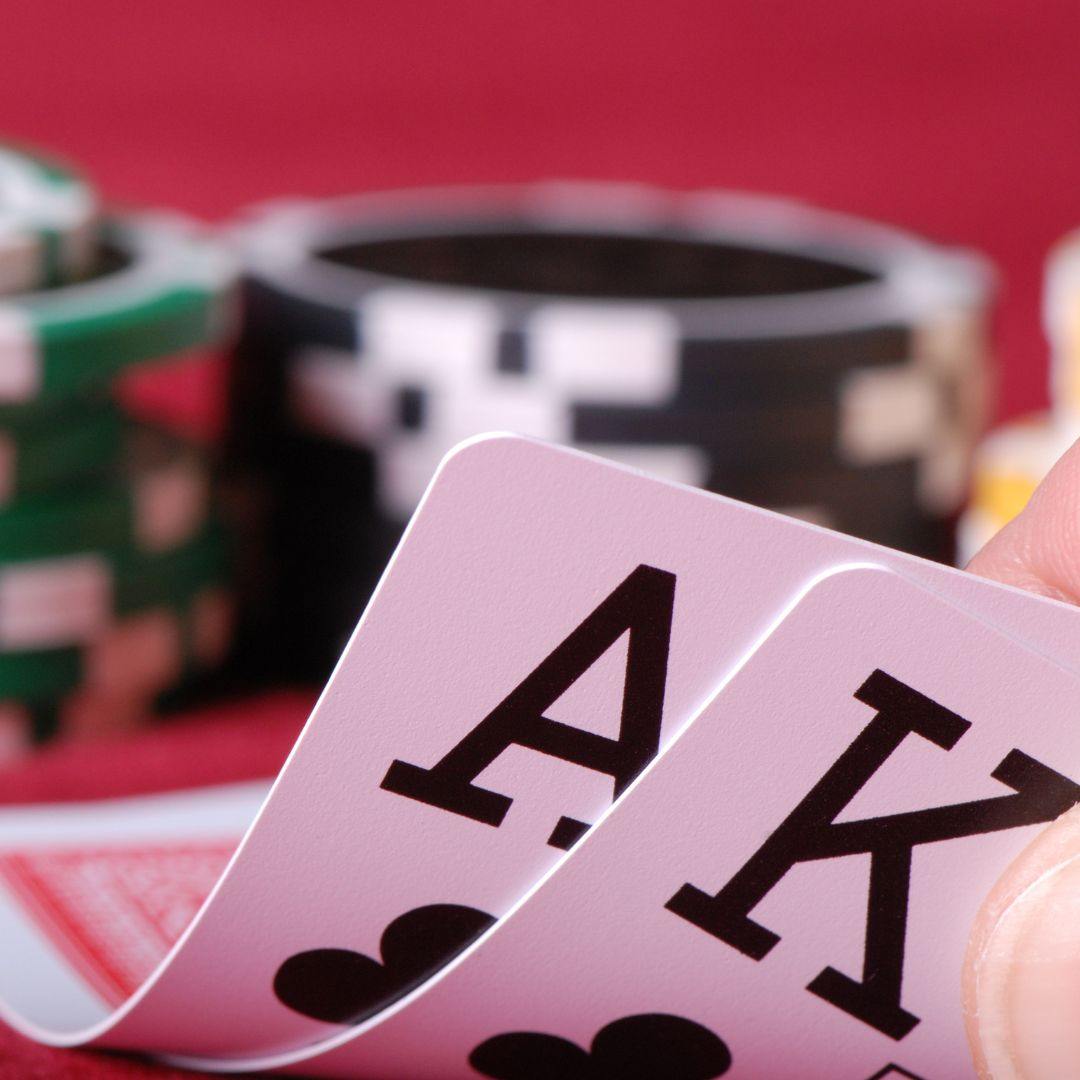 a close up of an ace and king of clubs playing cards with poker chips stacked in the blurred background