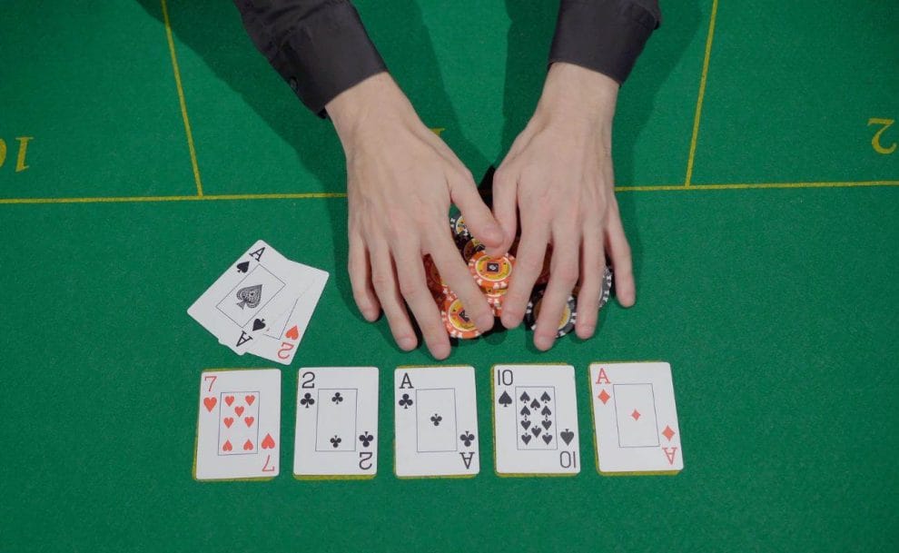 a top view of a poker player pulling the pot of poker chips towards themselves after winning with a full house on a poker table