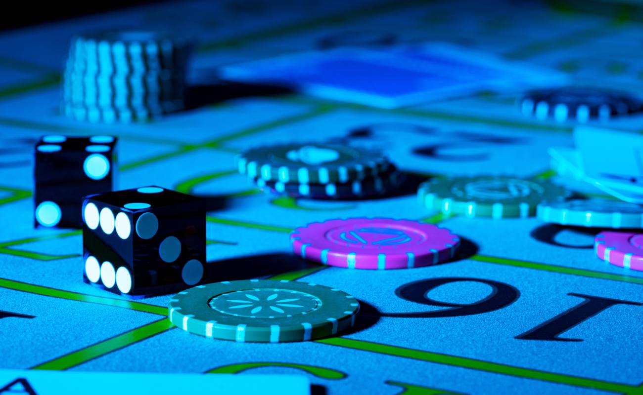 A blue-lit craps table with dice and casino chips.