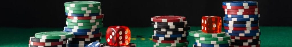 stacks of poker chips and red dice on a green felt poker table