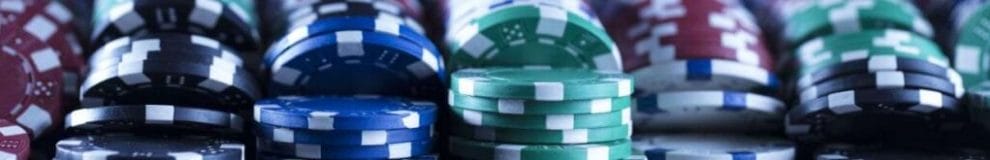 An extreme closeup of rows of red, black, blue, white, and green poker chips.