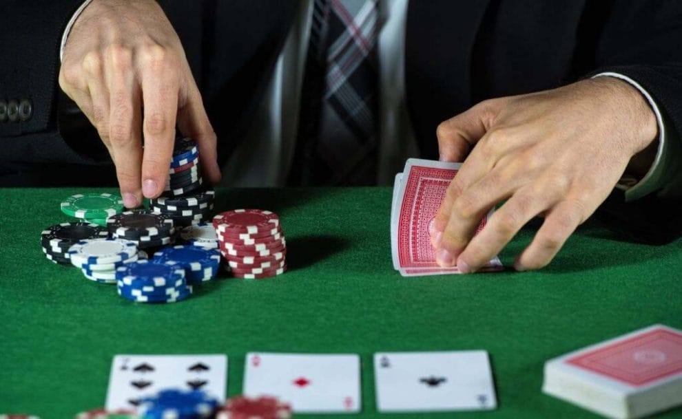 A poker player places his bet with his right hand while lifting his cards to peak at them with his left hand.