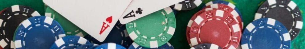 Poker chips and a pair of aces on a green felt poker table.