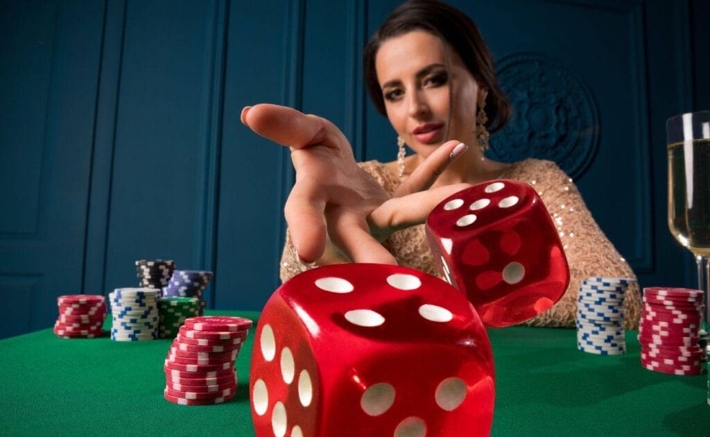 A lady throwing red six-sided dice forward on a green felt poker table with stacks of poker chips on it 