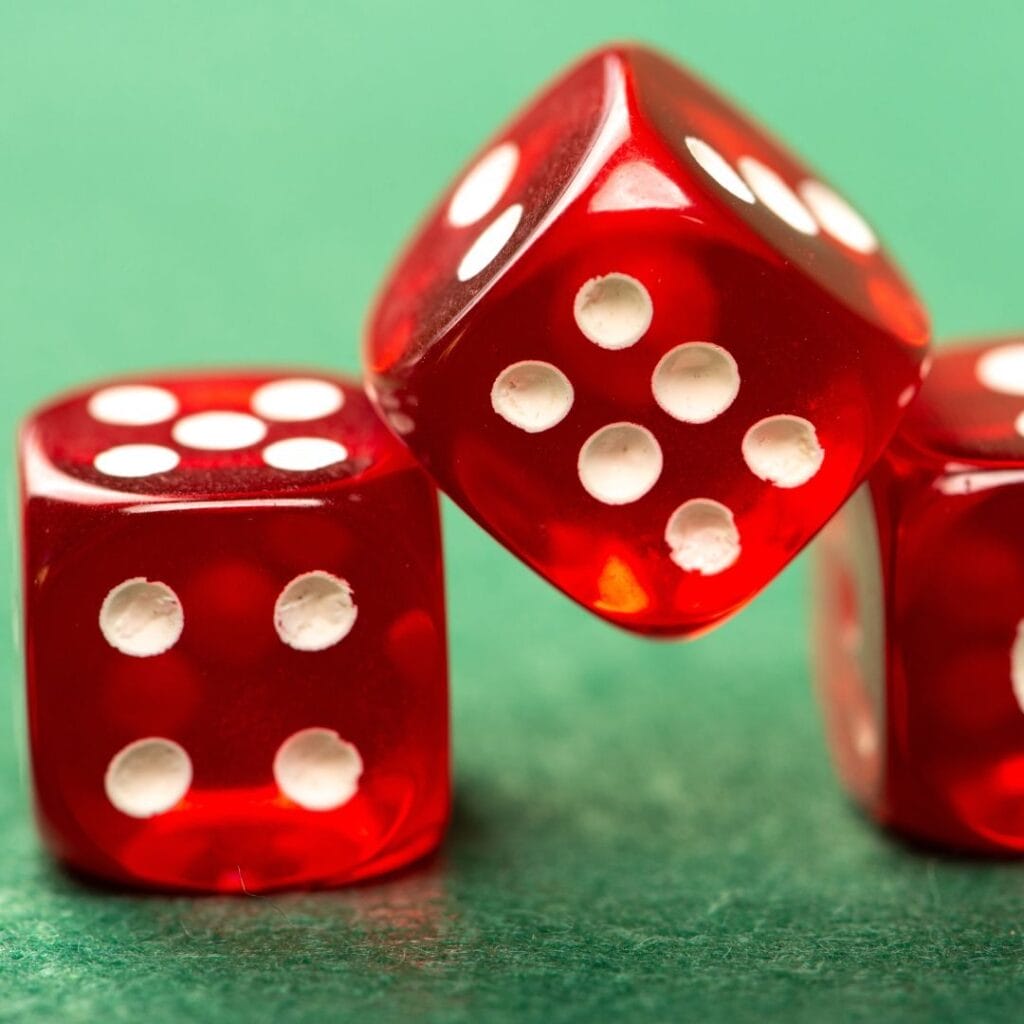 close up of three red dice on a green felt poker table