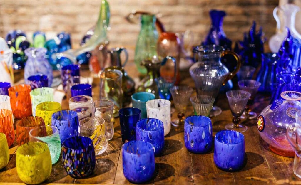 Colorful glasses and vases on a wooden table.