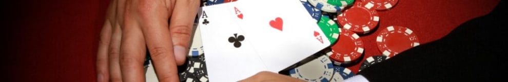 A poker player pulling poker chips with two aces on top towards themselves.