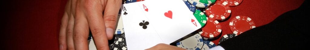 A poker player pulling poker chips with two aces on top towards themselves.