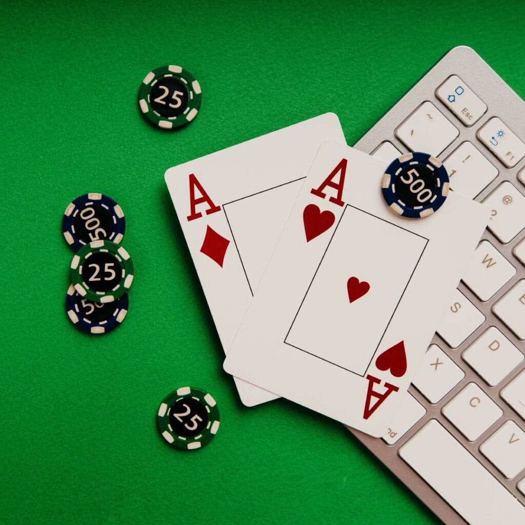 Playing cards and chips on the white keyboard on the green table.