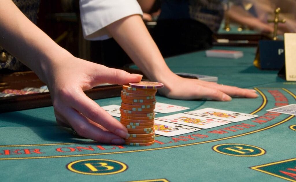 A dealer moves casino chips on a blackjack table.