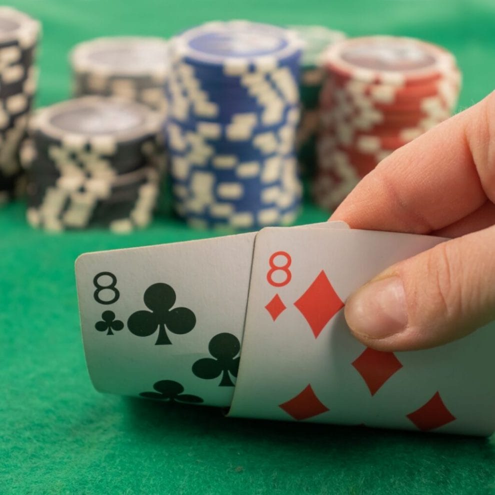 a pair of eights in the hands on the background of poker chips