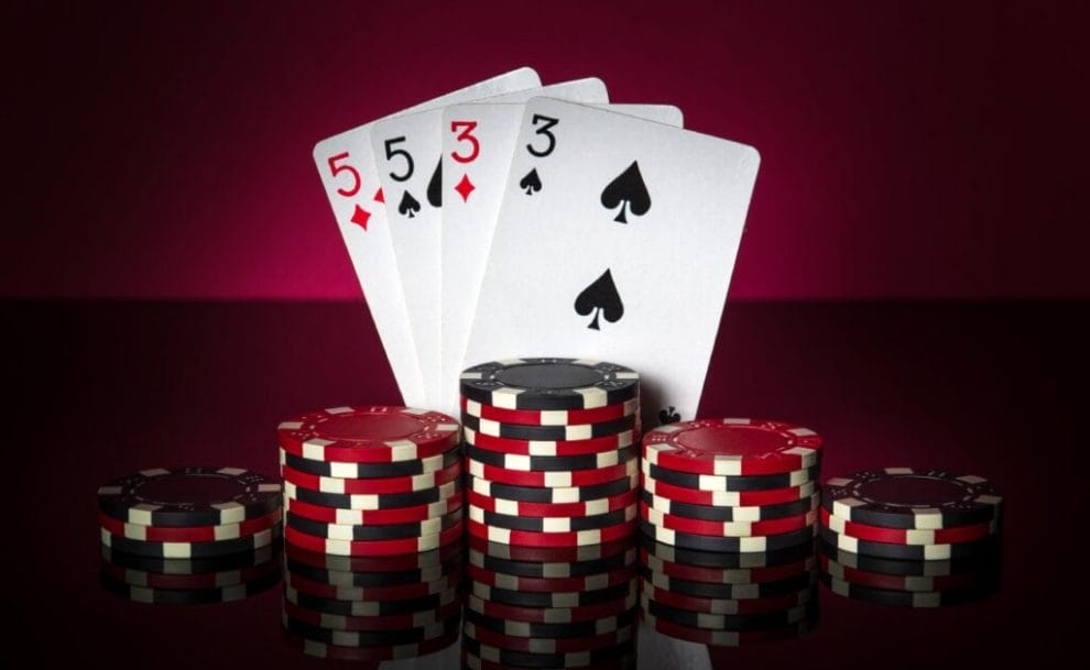 Poker cards and casino chips on a red surface.