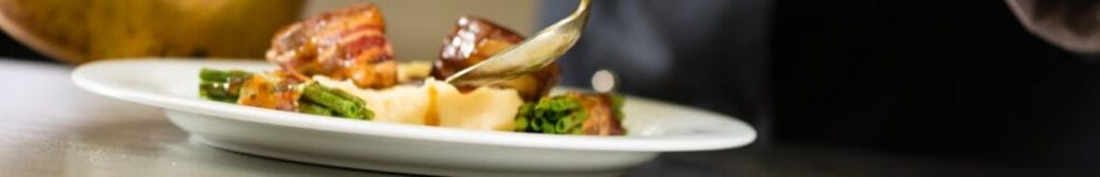 A chef pours sauce over mashed potatoes.