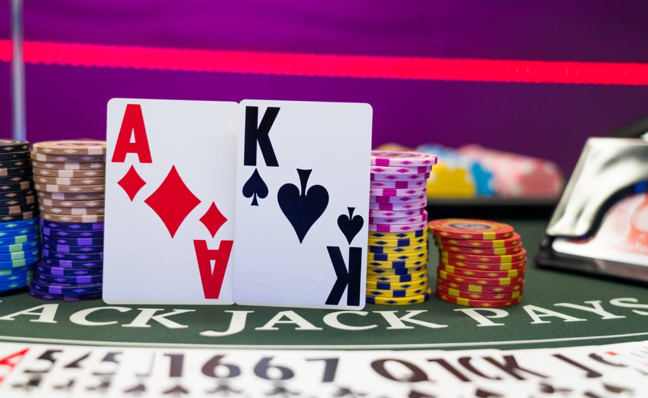 An ace and king playing card on a blackjack table with casino chips. 