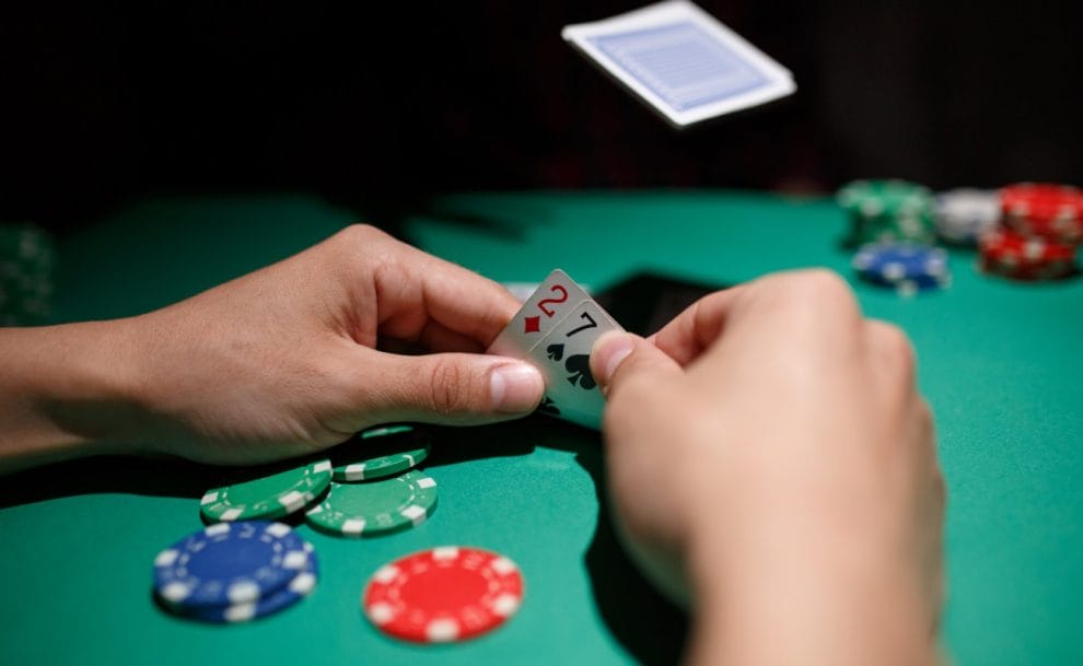 Hands holding playing cards at a poker table.