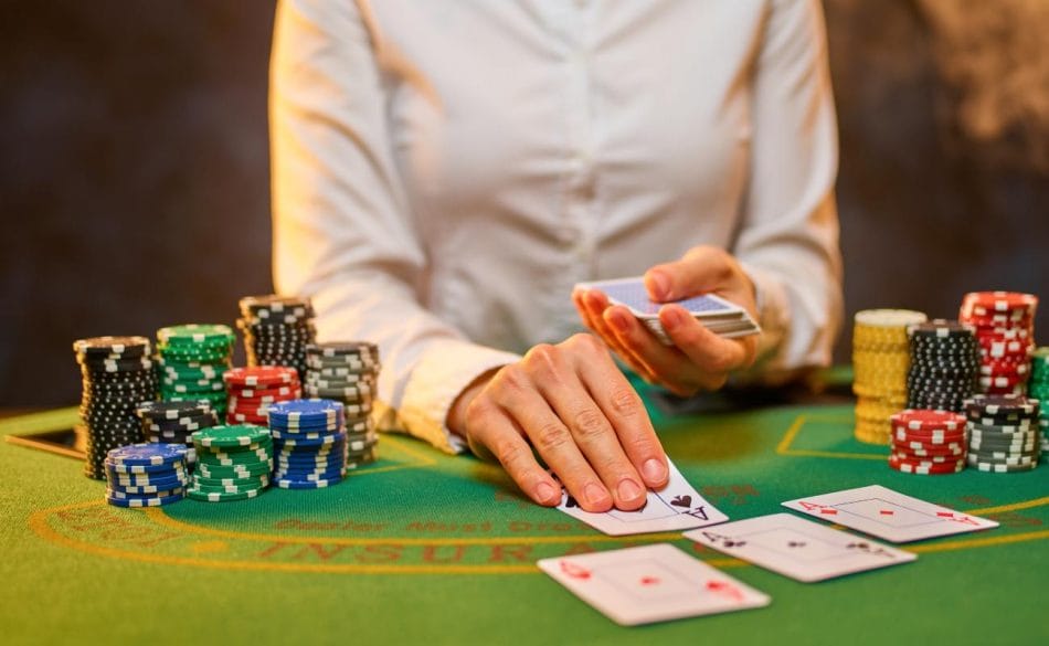 A poker dealer places cards on a green felt table.