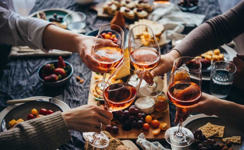 A group of friends toasting with glasses of wine over a cheese board.