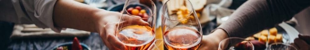 A group of friends toasting with glasses of wine over a cheese board.