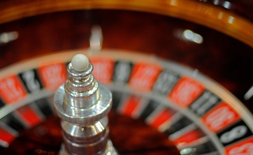close up of a little white roulette ball on top of a roulette turret with the roulette wheel blurred in the background 