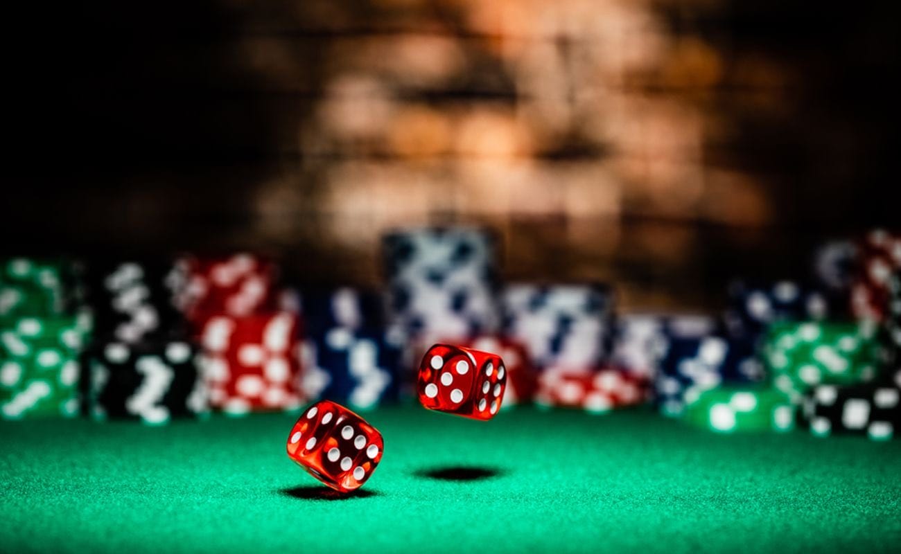 Two dice rolling on a casino table surrounded by casino chips.